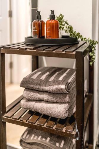 a pile of towels on a shelf with two soap bottles at -Air Con- 3BD Mews House - Kensington Palace! in London
