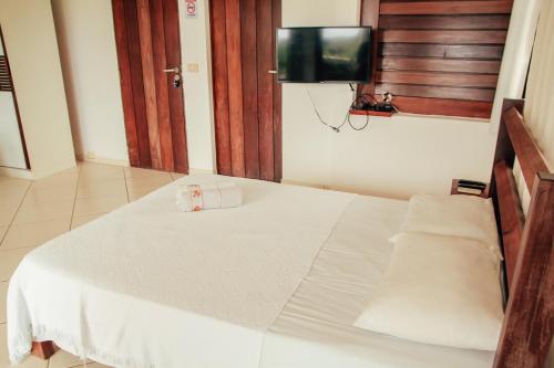 a white bed in a room with a tv at Pipa Panorama Aparthotel in Pipa
