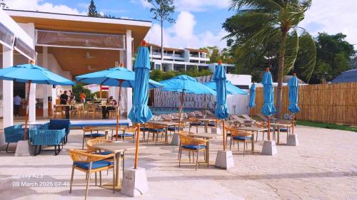 a group of tables and chairs with blue umbrellas at Three Trees Samui Resort - Sarocha Villa in Lamai