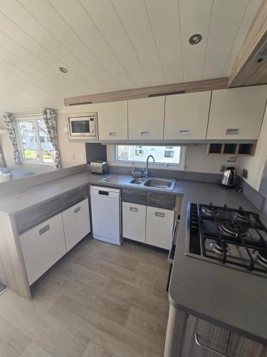 a kitchen with white cabinets and a stove top oven at Haven Burnham on sea 16 Elm Grove in Burnham on Sea