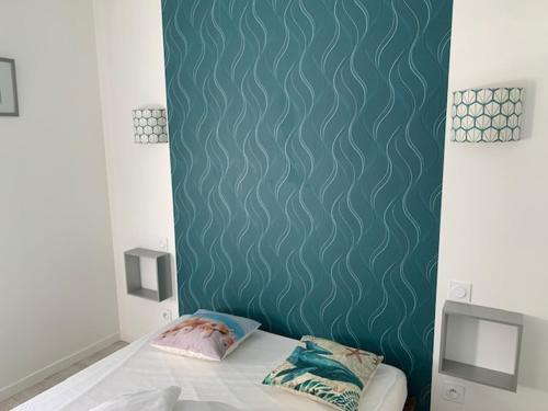 - une chambre dotée d'un lit avec un mur vert dans l'établissement La maison du Moulin, à Jard-sur-Mer