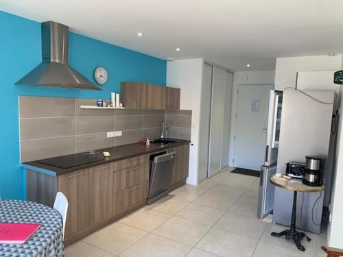 une cuisine avec un comptoir et un mur bleu dans l'établissement La maison du Moulin, à Jard-sur-Mer