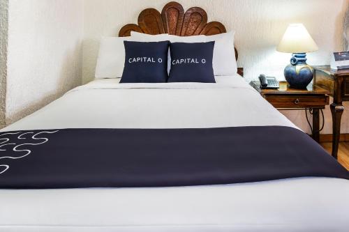 a bedroom with a large bed with blue and white pillows at Capital O Hotel Central, Xalapa in Xalapa