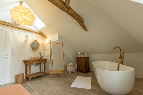 ein Badezimmer mit großer Badewanne auf einem Dachboden in der Unterkunft La Demeure en Périgord Meublé Tourisme 5 étoiles Luxe in Anlhiac