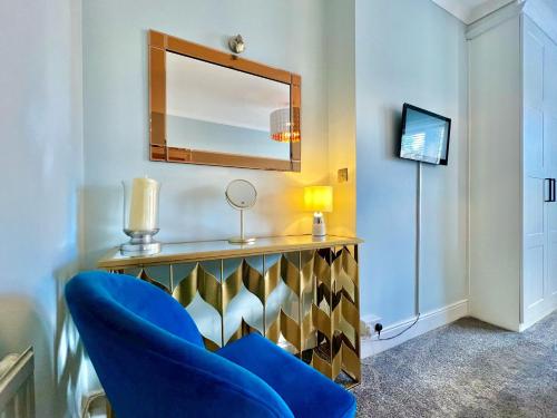 a room with a blue chair and a mirror at Arnold House in the heart of Calverley village in Calverley