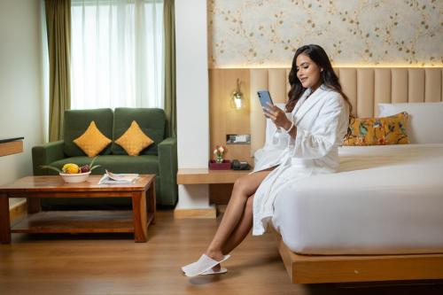 a woman sitting on a bed looking at her cell phone at Summit Grand Resort & Spa in Gangtok
