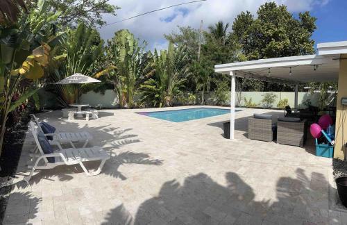 a patio with a pool and chairs and an umbrella at Great 4b2b getaway with heated salt water pool in Fort Lauderdale