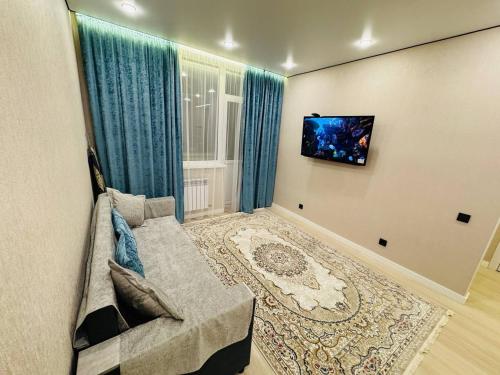 a living room with a couch and a tv at Syganak Apartments in Astana
