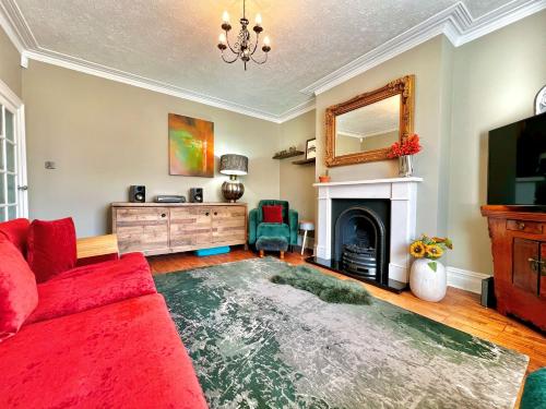 a living room with a red couch and a fireplace at Arnold House in the heart of Calverley village in Calverley