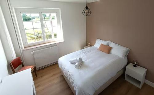 une chambre avec un lit blanc et une fenêtre dans l'établissement La trouvaille des retrouvailles, à Saint-Marc-le-Blanc