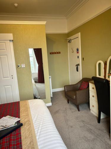 a bedroom with a bed and a chair and a door at Daviot Guest House in Ayr