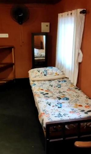 a bed in a room with a window and a mirror at Zyamadhari in Mananthavady