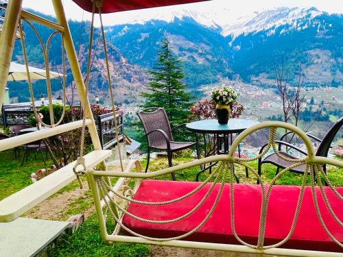 a red bag sitting on a swing with a table at 4 Bedroom Luxury Bungalow In Manali With Beautiful Scenic Mountain & Orchard View - #Private Bungalow #Premium Big rooms #Parking #Guest Preferred in Manāli