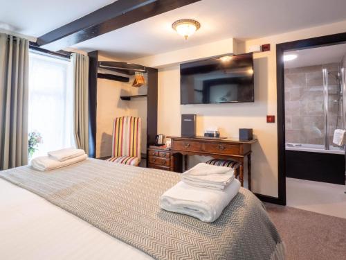 a bedroom with two beds with a television and a desk at The Black Boy Inn in Caernarfon