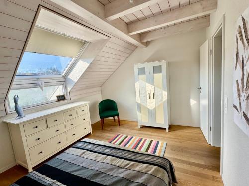 a bedroom with a window and a dresser and a chair at Grosse Wohnung mit Sauna in Huttwil