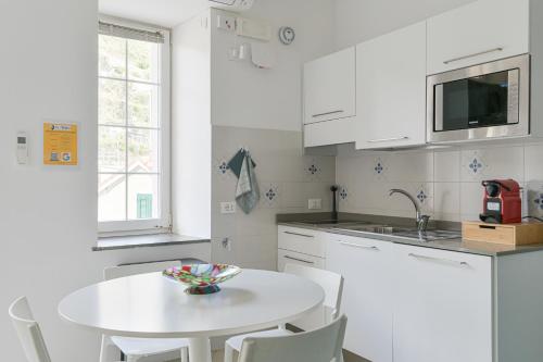 a white kitchen with a white table and a sink at Ca' del Monica in Manarola