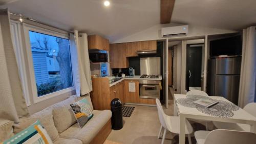 Una sala de estar y una cocina con un sofá y una mesa. en Mobihome les sables du midi, en Valras-Plage