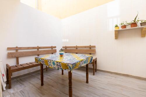 a table in a room with two benches and a table with at Quiet Traditional Stay - Rabat 3-Bedroom Apartment in Ħal-Bajjada