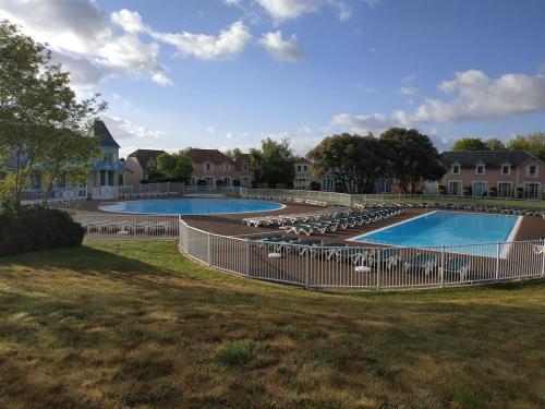 - deux piscines avec des chaises dans la cour dans l'établissement Maison 6-8 pers - 3 chbres - mer - piscine - golf, à Talmont-Saint-Hilaire