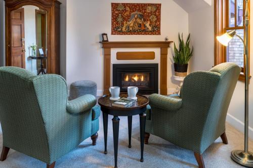 a living room with two chairs and a fireplace at Arch Cape Inn and Retreat in Arch Cape
