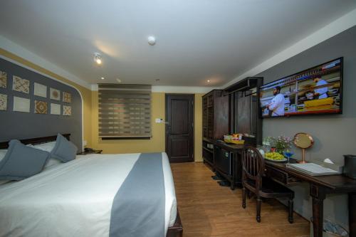 a bedroom with a bed and a desk and a television at Hoianan Boutique Hotel in Hoi An
