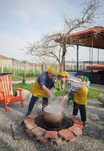 two people cooking food in a pot on a fire pit at Winery Matisi in Babaneuri