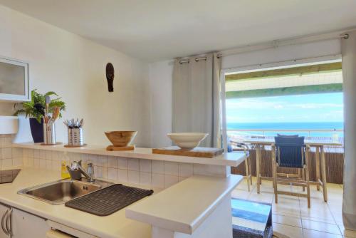 a kitchen with a sink and a view of the ocean at L'horizon - T2 Duplex - Vue mer à 180 in Saint-Gilles les Bains