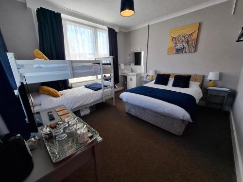 a bedroom with two bunk beds and a table at Westbrook Lodge Guest House in Margate