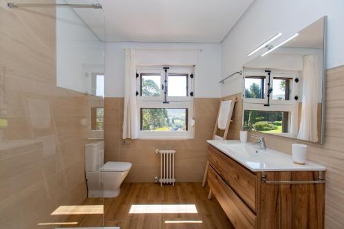 a bathroom with a sink and a toilet and windows at Finca Tolombreo Casa Gabriel in Cudillero
