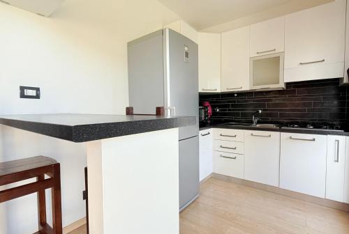 a kitchen with white cabinets and a black tile wall at Da Elisa MareSol in Quartu SantʼElena
