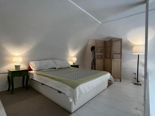 a white bedroom with a bed and two lamps at La Cupoletta Ponza in Arcipelago Ponziano
