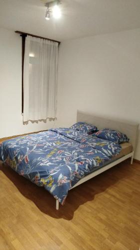 a bedroom with a bed with a blue comforter and a window at Belle maison in Aalst