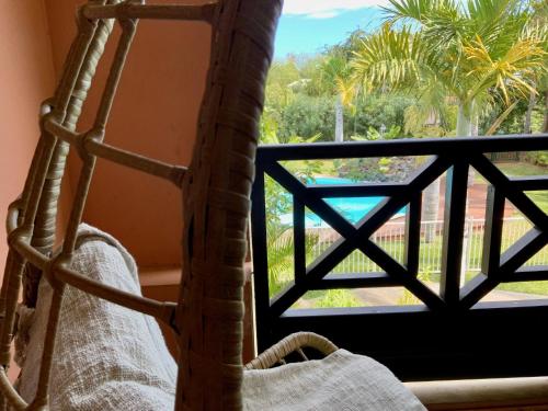 a bedroom with a view of a palm tree from a window at Le Sable Blanc - piscine - parking - clim - wifi in Saint-Gilles-les-Bains