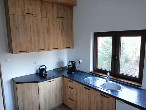 a kitchen with wooden cabinets and a sink and a window at Osada Blanka Leśny Zakątek Jezioro Rzeka Swornegacie in Swornegacie 