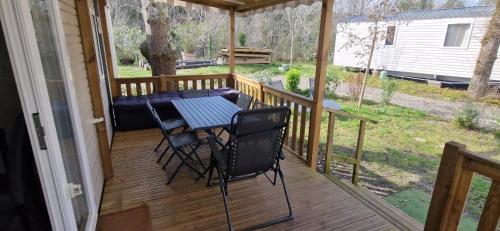 a screened porch with a table and chairs on it at Cosy mobil home 3Ch en forêt, parking inclus, plage à 15mn à pied in Capbreton