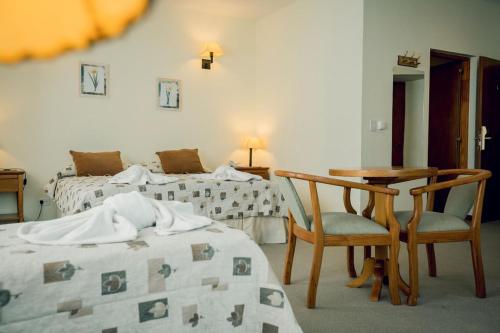 a bedroom with two beds and a table and chairs at Hotel Spa Nieves Del Cerro in Caviahue