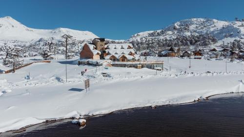 a snow covered village with a building in the snow at Hotel Spa Nieves Del Cerro in Caviahue