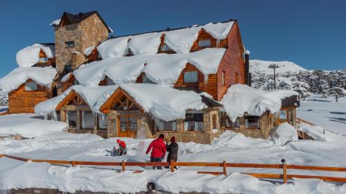 a group of people standing in front of a house covered in snow at Hotel Spa Nieves Del Cerro in Caviahue
