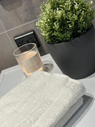 a white towel and a glass of candle and a potted plant at Kaldvell Stays Central - New Apartment in Lillesand