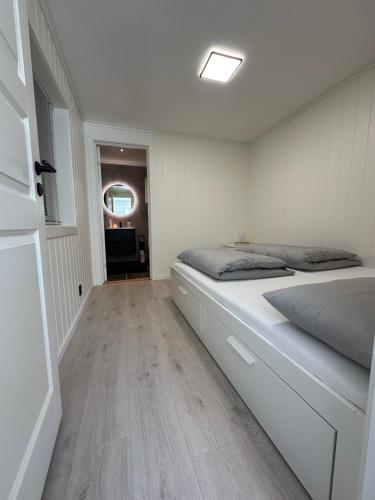 a white bedroom with a bed and a window at Kaldvell Stays Central - New Apartment in Lillesand