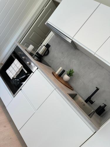 a white kitchen with a counter and a stove at Kaldvell Stays Central - New Apartment in Lillesand