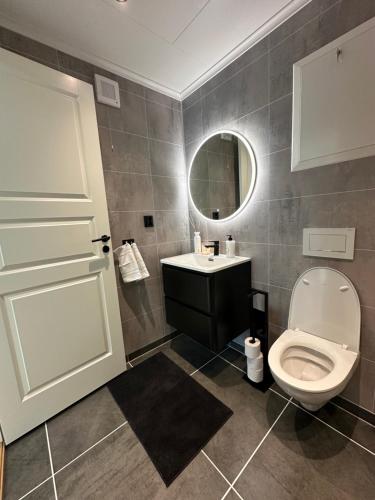 a bathroom with a toilet and a sink and a mirror at Kaldvell Stays Central - New Apartment in Lillesand