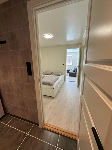 a small room with a bed and a door to a bedroom at Kaldvell Stays Central - New Apartment in Lillesand