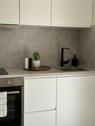 a kitchen with white cabinets and a sink at Kaldvell Stays Central - New Apartment in Lillesand
