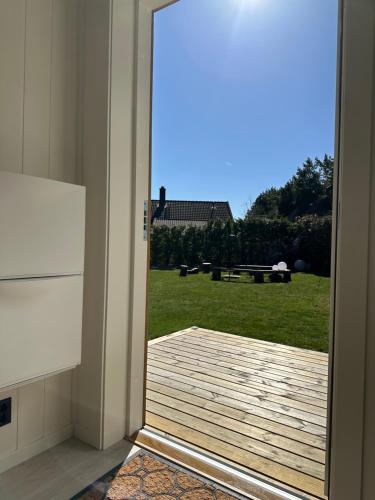 an open door to a deck with a view of a yard at Kaldvell Stays Central - New Apartment in Lillesand