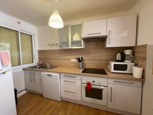 une cuisine avec des armoires blanches et un micro-ondes dans l'établissement T3 Ax-les thermes centre, à Ax-les-Thermes