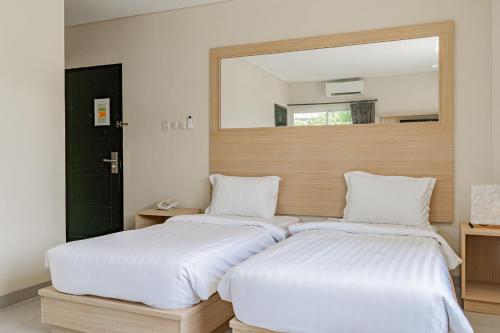 two beds in a room with a mirror on the wall at Collection O Kuta Near Airport Ngurah Rai in Kuta