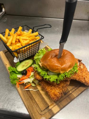 a sandwich and french fries on a cutting board with a knife at Alpen Hotel Martin in Nesselwang