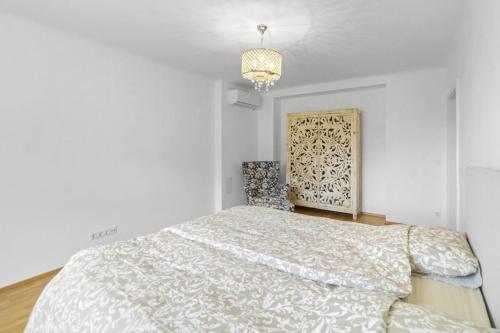 a white bedroom with a bed and a chandelier at Golden Stay Residence in Brunn am Gebirge