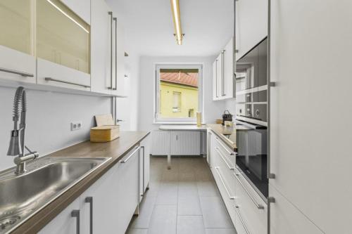 a white kitchen with a sink and a window at Golden Stay Residence in Brunn am Gebirge